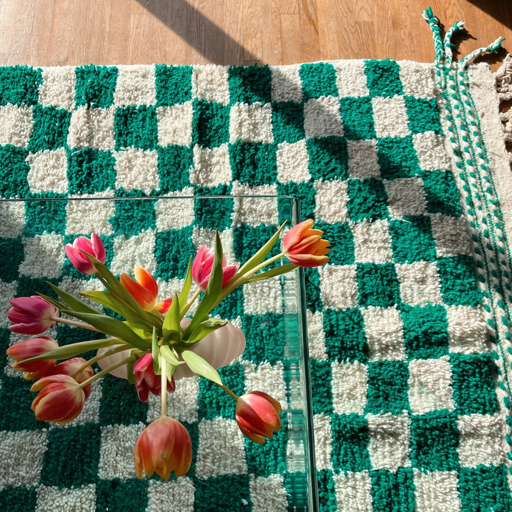 tapis berbère en damiers vert sapin et blanc avec tulipes posées sur une table en verre. Tapis berbère artisanal à carreaux vert et blanc. Green and white checkered rug. Handmade Berber rug 
