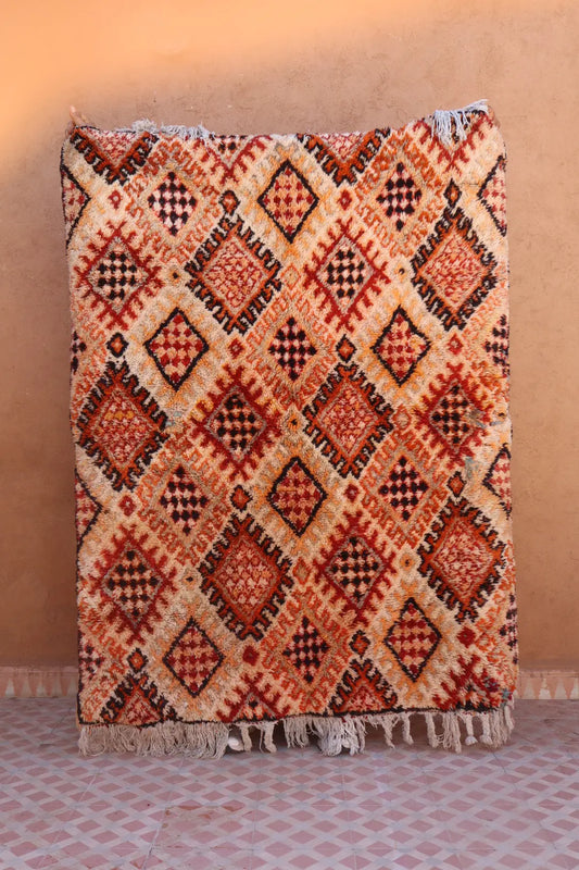 Tapis berbère vintage aux motifs traditionnels, couleurs chaudes rouge brique, orange et beig